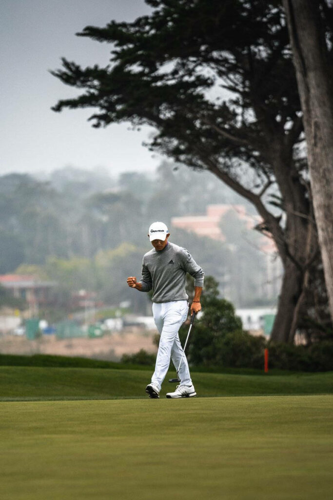 Collin Morikawa walking on lush golf course with club misty trees calm focus wallpaper