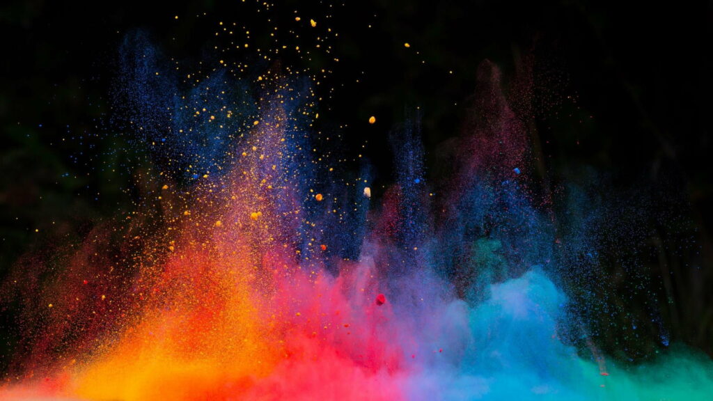 Vibrant color explosion of yellow orange red and blue powder on black background high speed photo Wallpaper