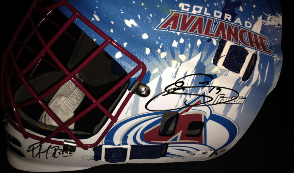 Close-up of Colorado Avalanche hockey helmet with autographs vibrant team logo wallpaper background