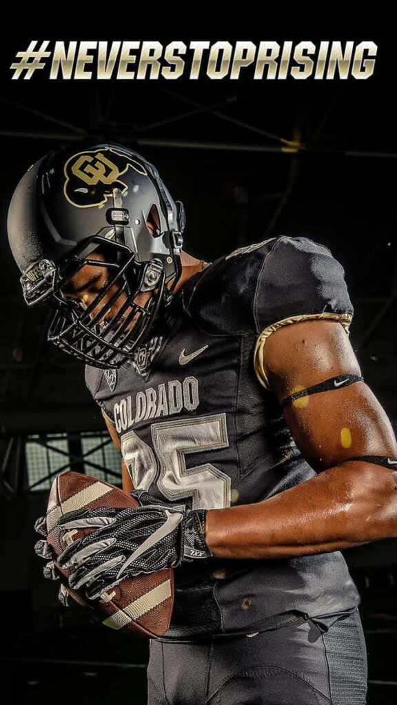 Determined Colorado Buffaloes football player in black and gold uniform with matte helmet intense focus Wallpaper