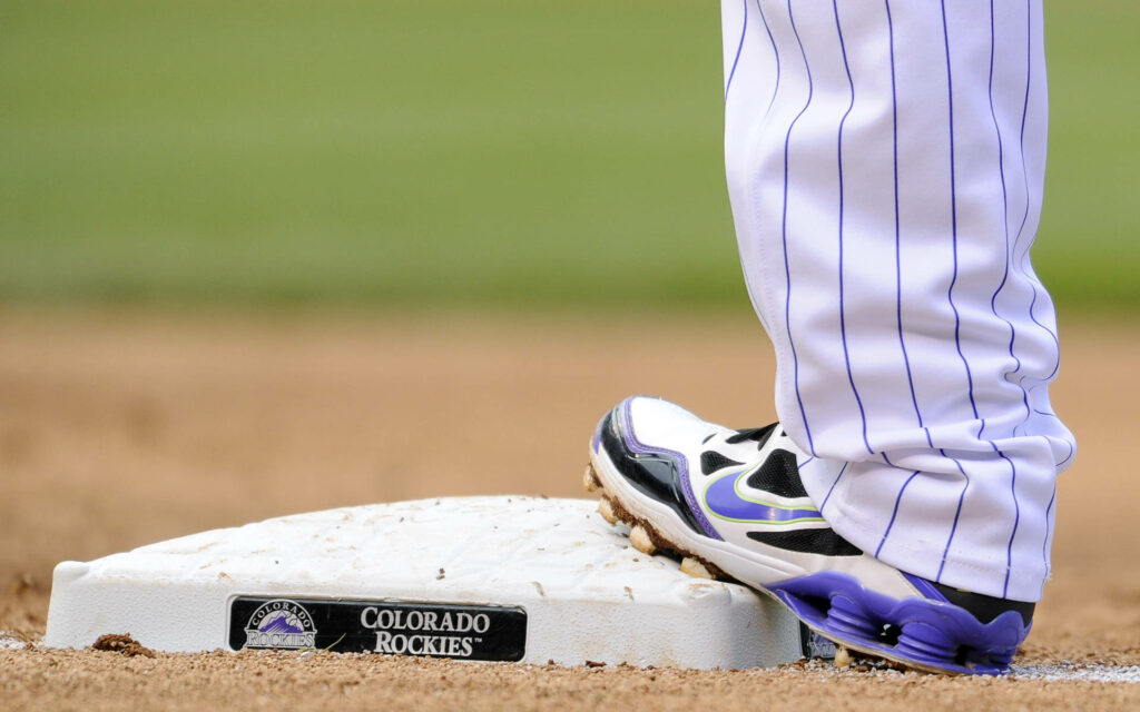 Close-up of Colorado Rockies player on base showing pinstripe uniform and purple cleats Wallpaper