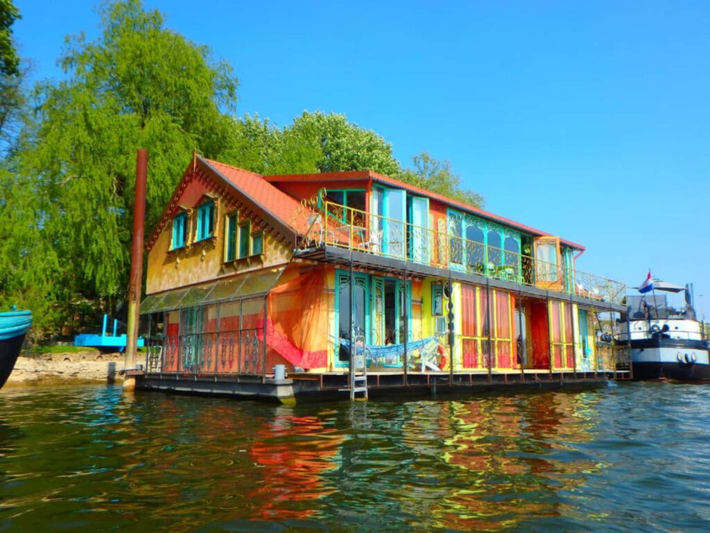 Colorful houseboat with bright walls and large windows on Arnhem water under clear blue sky Wallpaper