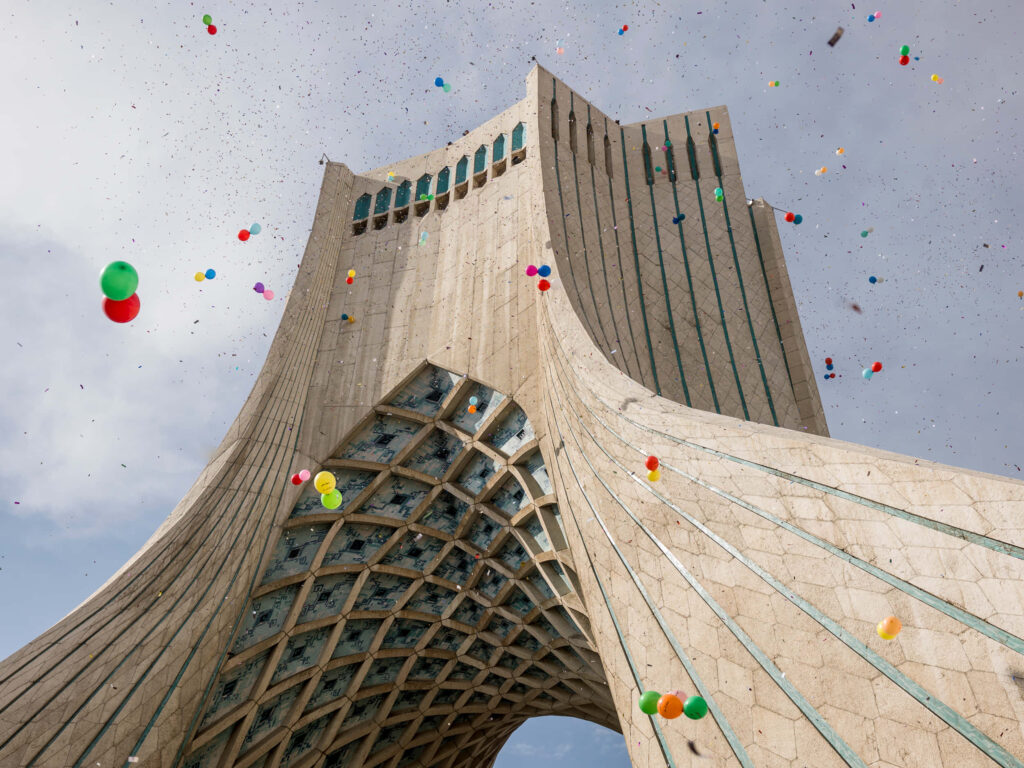 Colorful balloons rising near Azadi Tower festive sky background modern architecture wallpaper