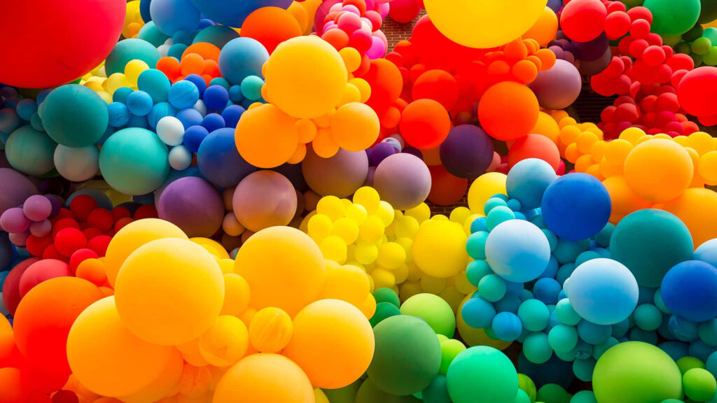 Colorful balloons floating upward against a bright blue sky joyful vibrant wallpaper background