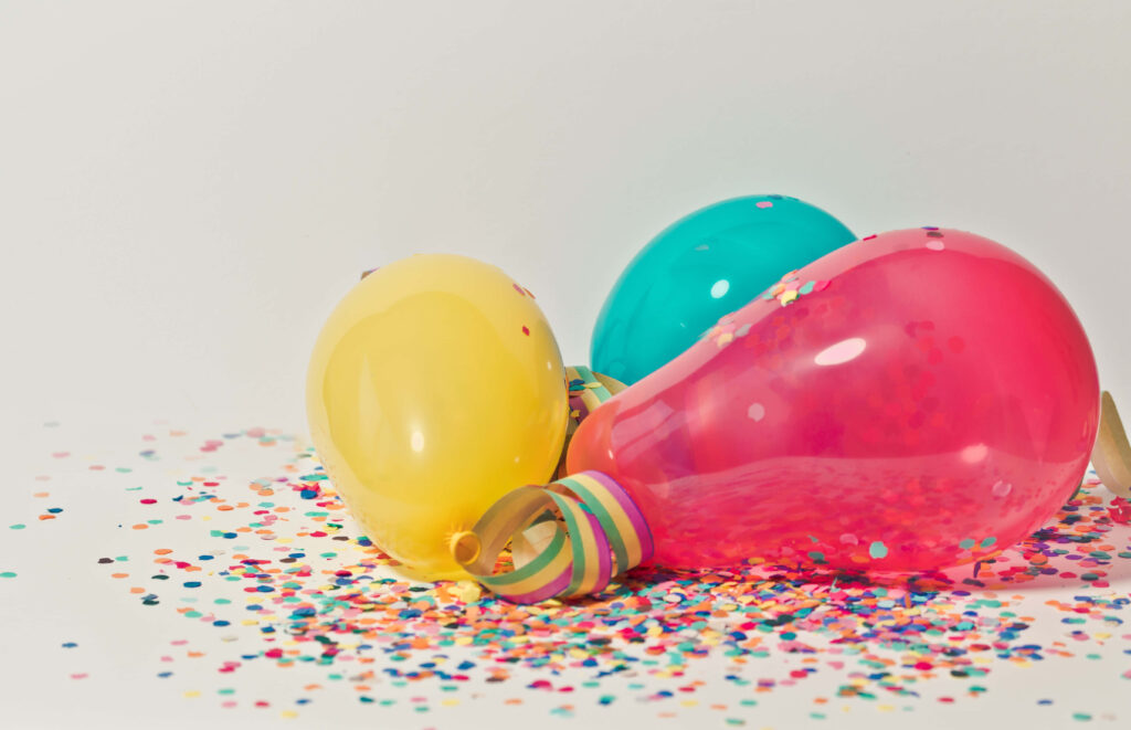 Colorful balloons and confetti on white background festive joyful wallpaper design celebration