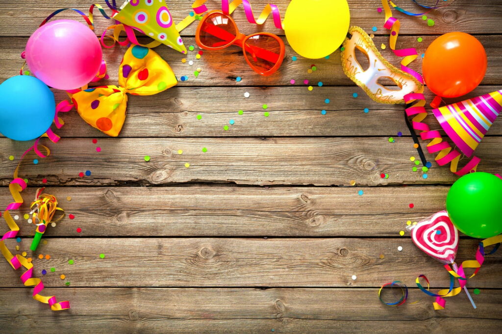 Vibrant birthday celebration flat lay with balloons party hats masquerade mask and heart candy Wallpaper
