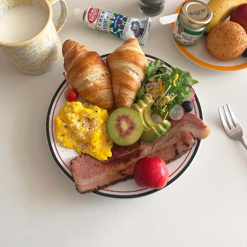 Vibrant Breakfast Plate: Croissants, Eggs, Bacon & Fresh Fruits Wallpaper