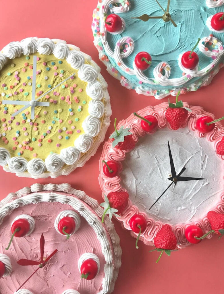 Colorful Cake-Style Clocks Wallpaper Against a Pink Backdrop