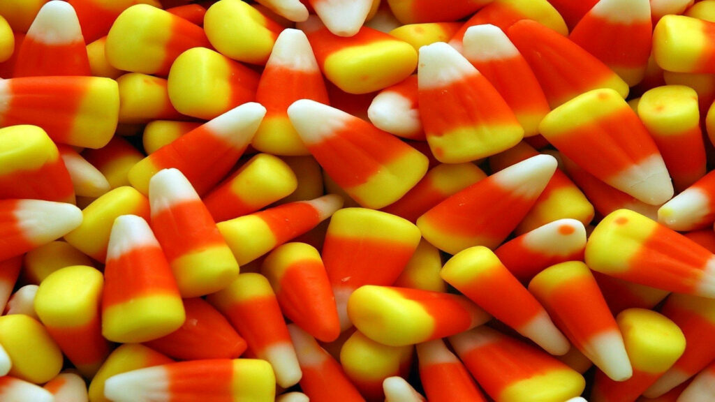 Close-up colorful candy corn wallpaper with vibrant yellow orange and white Halloween theme background