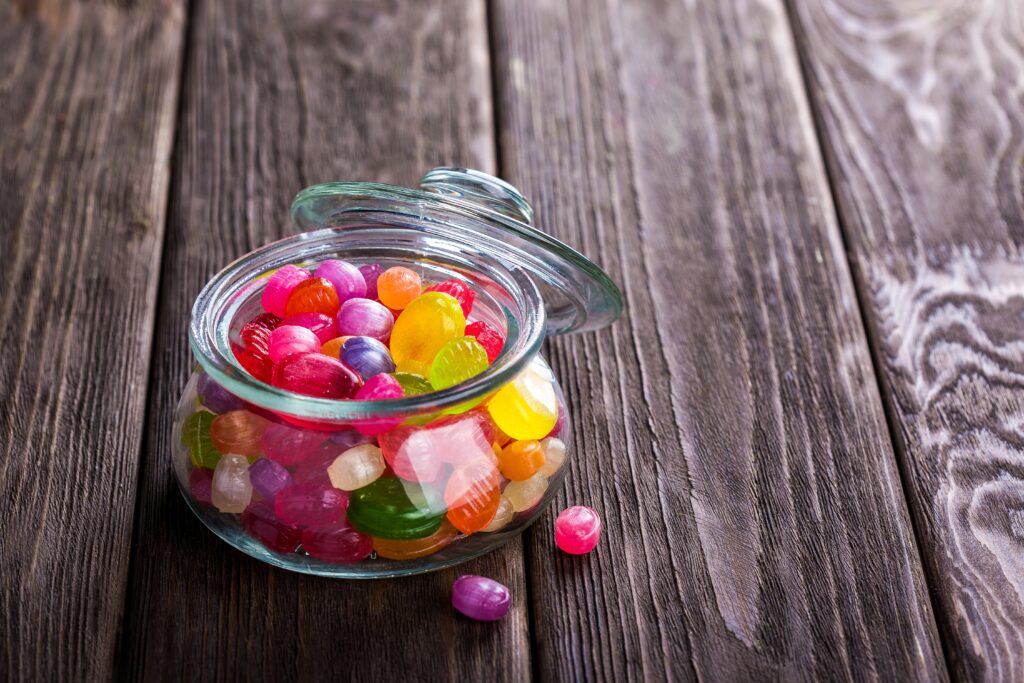 Colorful Candy Jar on Rustic Wood: Cheerful Wallpaper Background