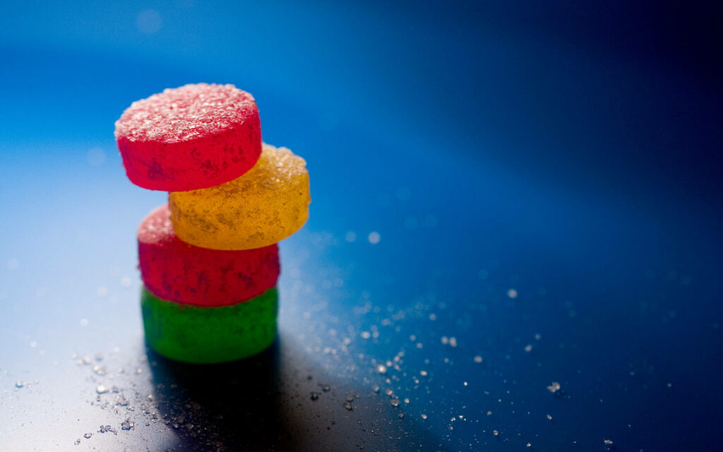 Colorful candy pile on smooth blue background with sugar crystals vibrant sweet wallpaper