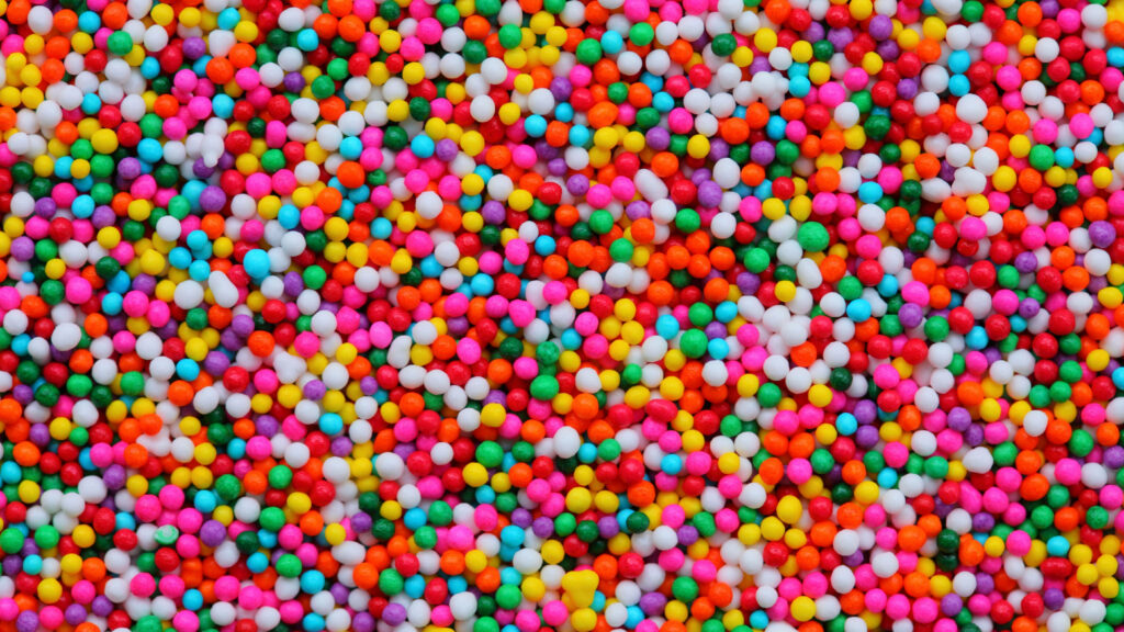 Colorful candy sprinkle wallpaper with vibrant multicolored round shapes cheerful background