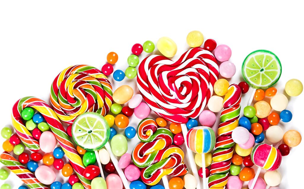 Colorful assorted candies with swirled lollipops heart-shaped sweets and gumdrops on white background Wallpaper