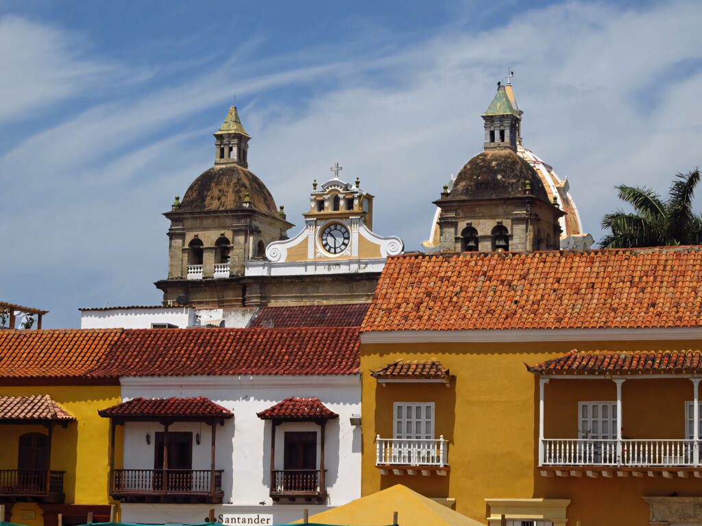 Colorful rooftops and colonial buildings at Cartagena Plaza de la Aduana with church domes and clock tower Wallpaper