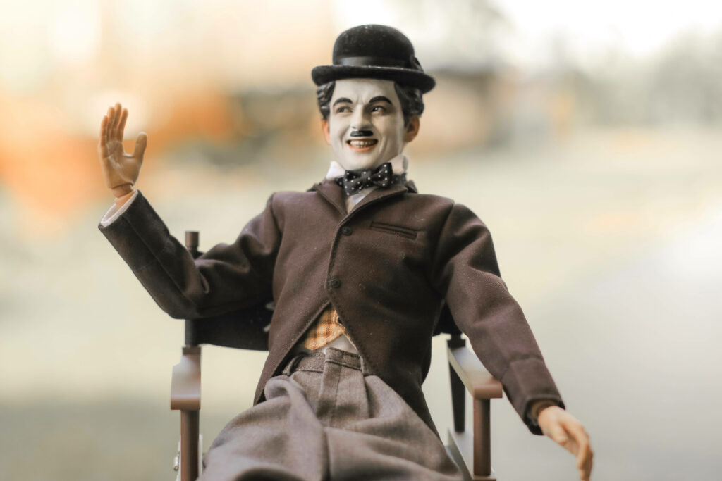 Charlie Chaplin figurine in classic attire sitting on chair with cheerful expression wallpaper
