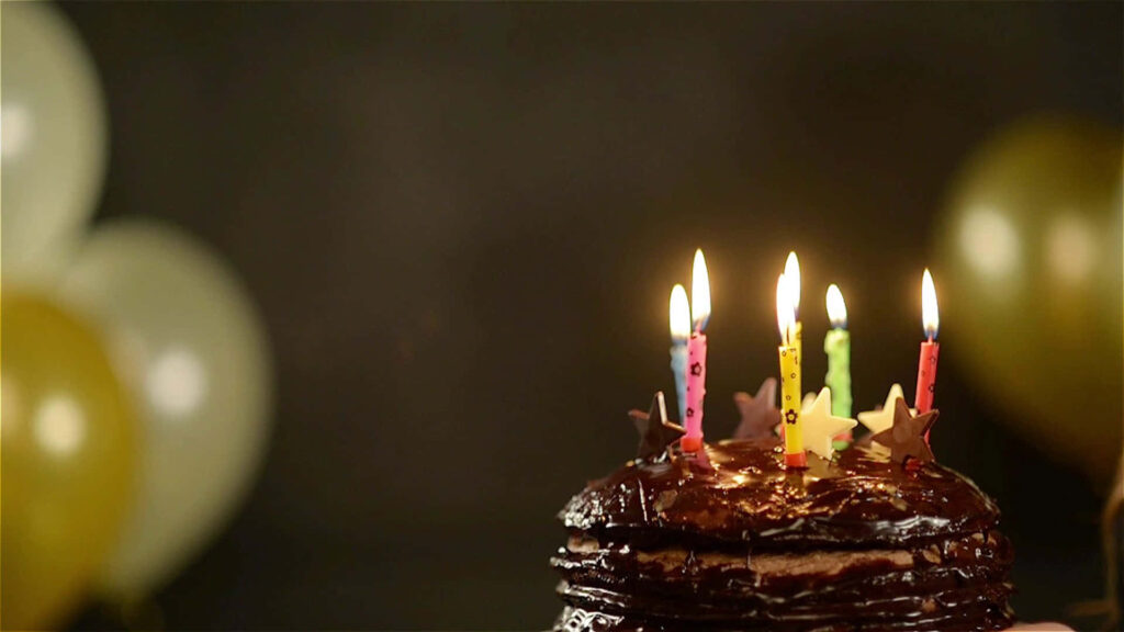 Festive Chocolate Birthday Cake with Colorful Candles & Balloons Wallpaper