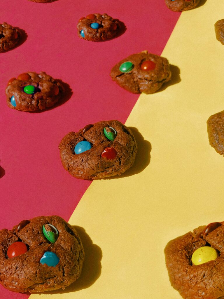 Vibrant Wallpaper: Chocolate Cookies with Colorful Dragees on Pink-Yellow