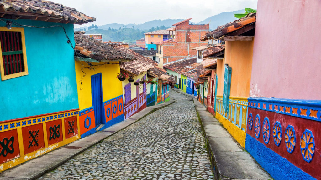Colorful Colombian street with traditional painted houses cobblestone path and mountain view Wallpaper
