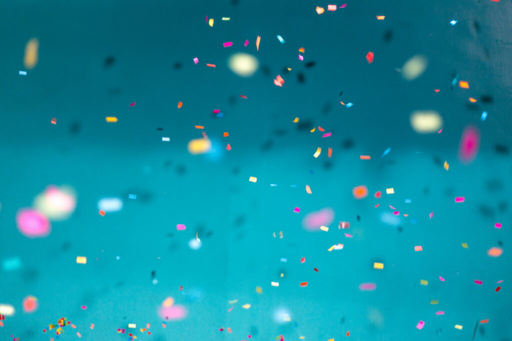 Colorful confetti floating on deep blue background with sharp focus and soft bokeh effect wallpaper