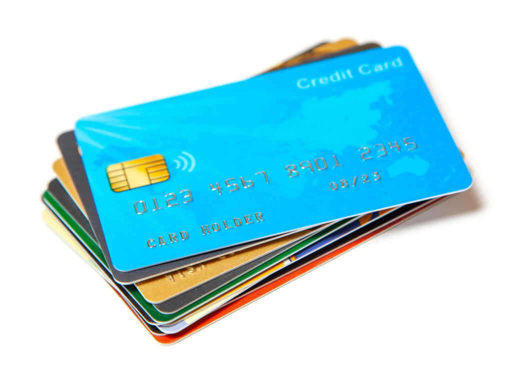Stacked colorful credit cards with metallic chips and embossed text on white background finance Wallpaper
