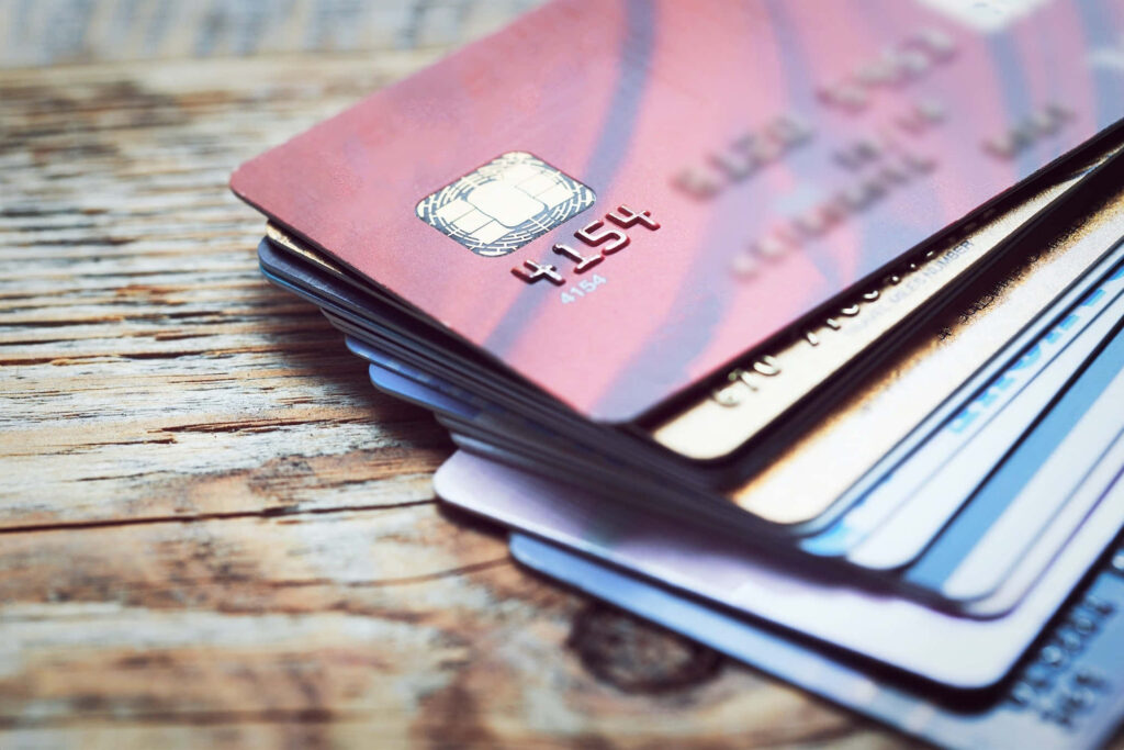 Stack of colorful credit cards on wooden table showing embossed details and chip technology Wallpaper