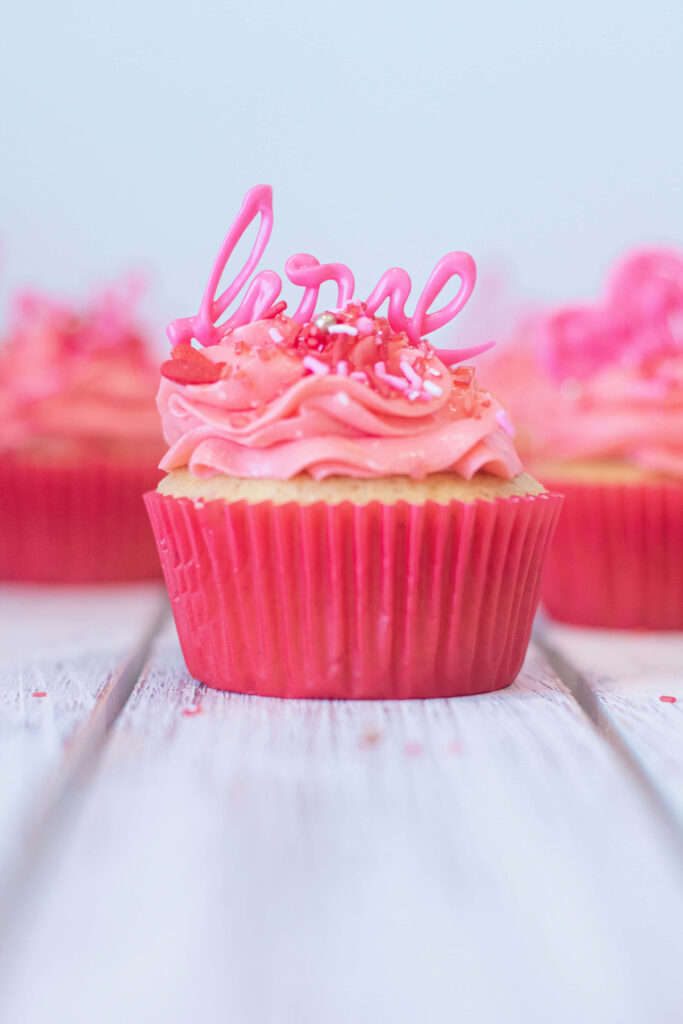 Colorful cupcakes with pink frosting and sprinkles on pastel background wooden surface wallpaper