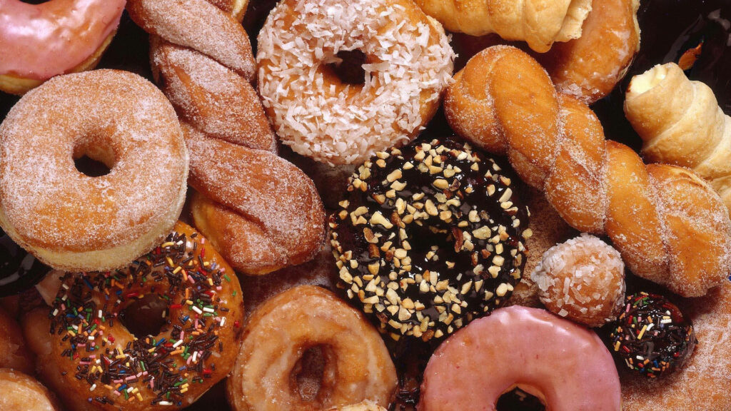 Colorful donut wallpaper with assorted flavors sprinkles glaze sugar and coconut toppings background