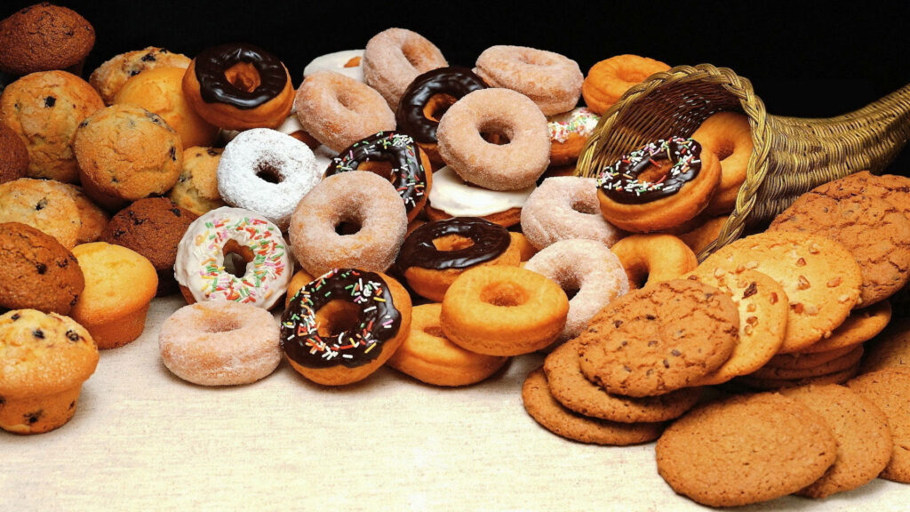 Colorful donuts chocolate chip cookies pastries on beige background bakery wallpaper design