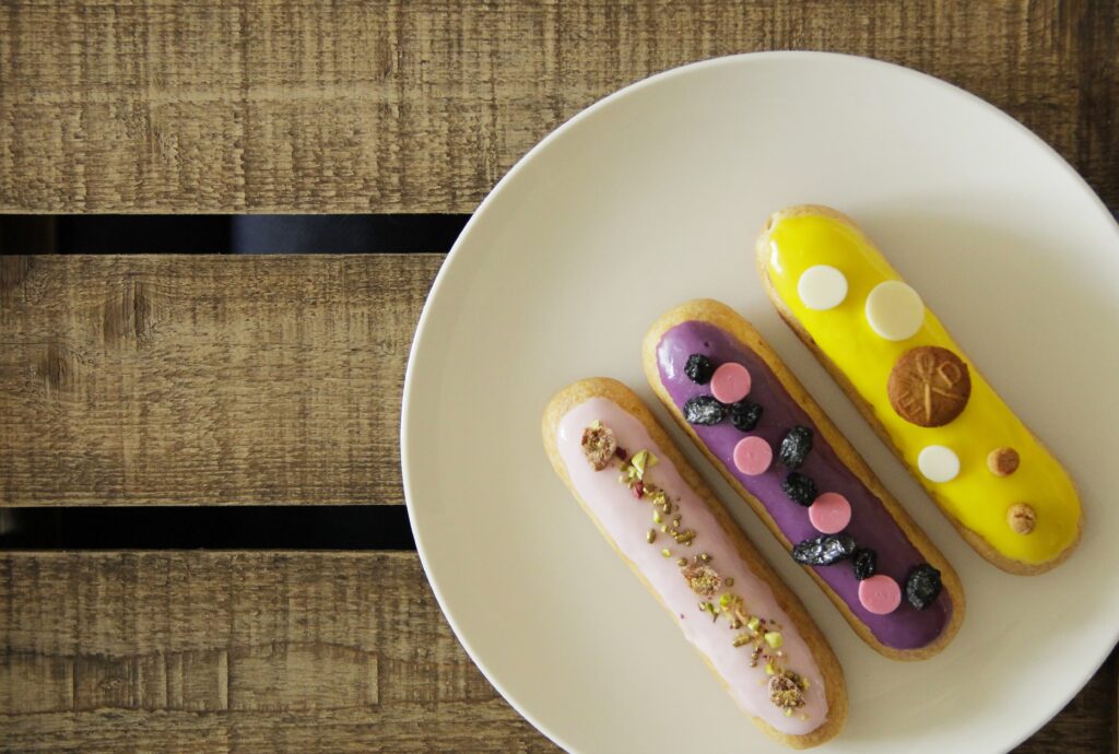 Vibrant Eclairs Wallpaper: Colorful Treats on Rustic Wood Background
