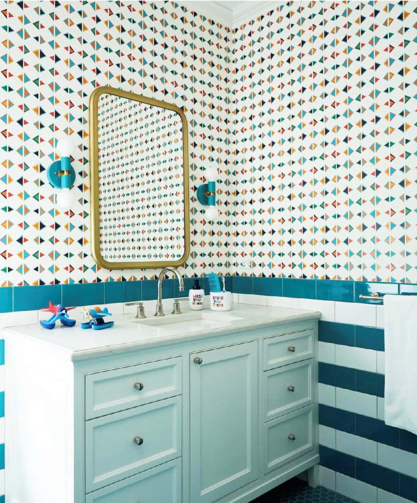 Playful geometric triangle bathroom wallpaper in teal orange blue with striped tiles and blue vanity