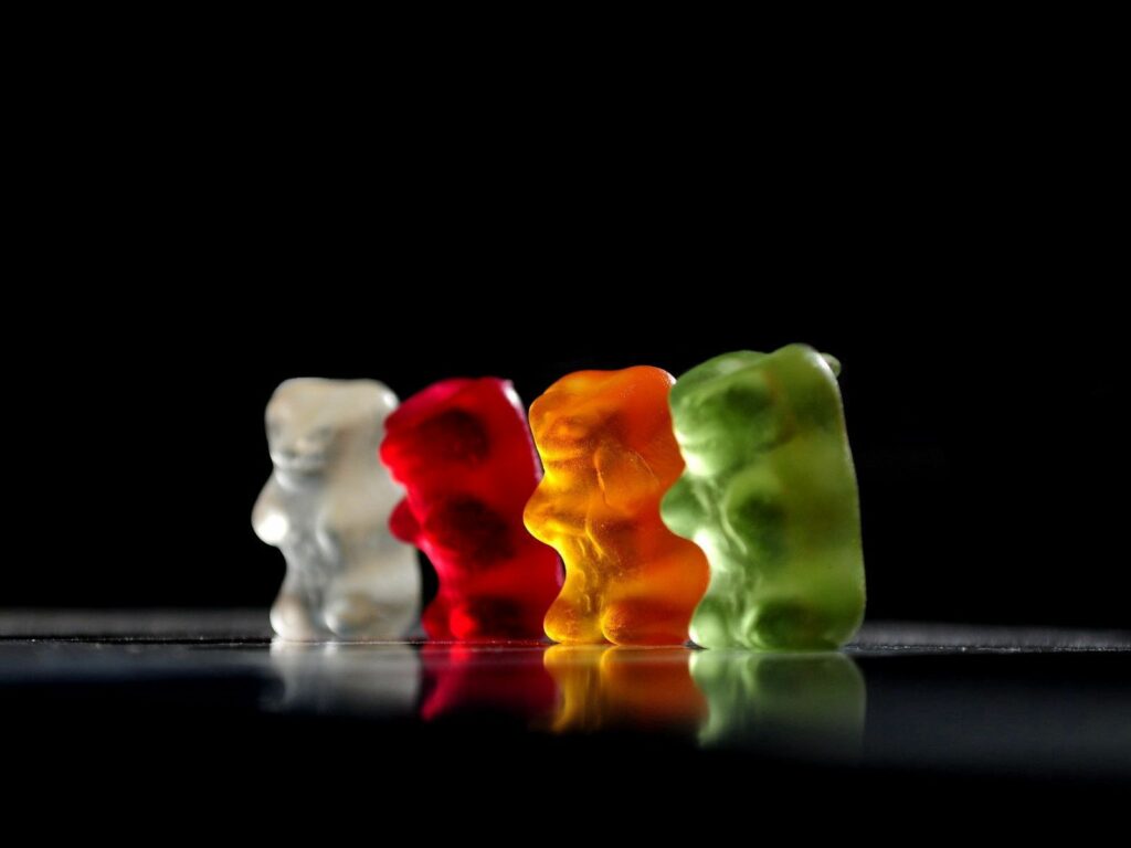 Colorful Gummy Bears Wallpaper: Sweet Transparent Design on Dark Background