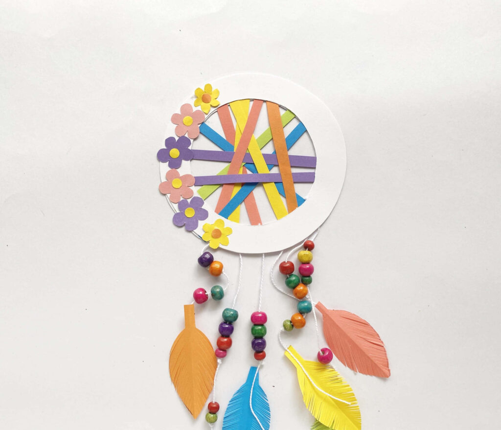 Handmade dreamcatcher with colorful paper feathers beads and flowers on white background wallpaper