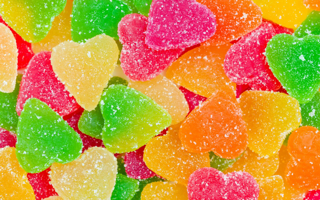 Colorful heart-shaped fruity jelly candies dusted with sugar bright vibrant wallpaper background