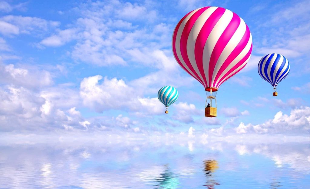 Three colorful striped hot air balloons over reflective water and bright blue sky wallpaper