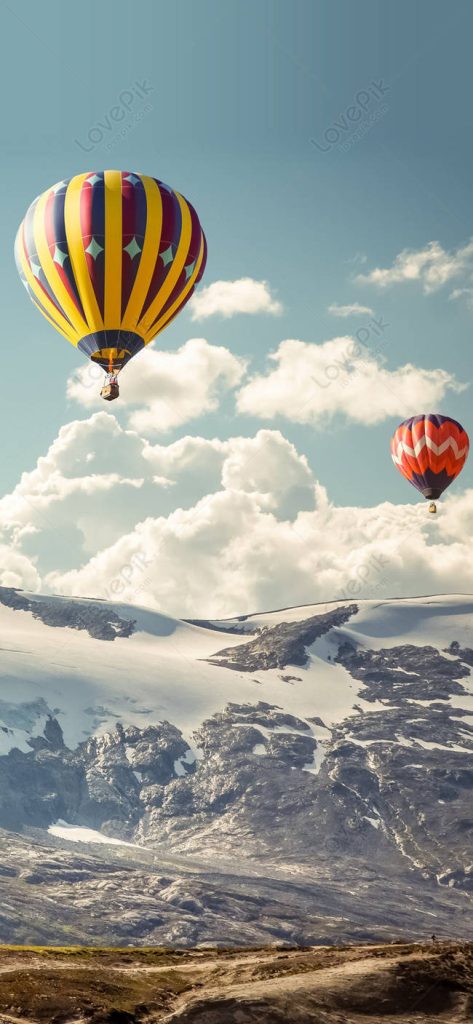 Colorful hot air balloons flying over snow-capped mountains under a bright blue sky wallpaper