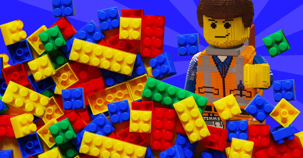 Colorful Lego bricks piled with smiling Lego figure in orange vest on blue wallpaper background