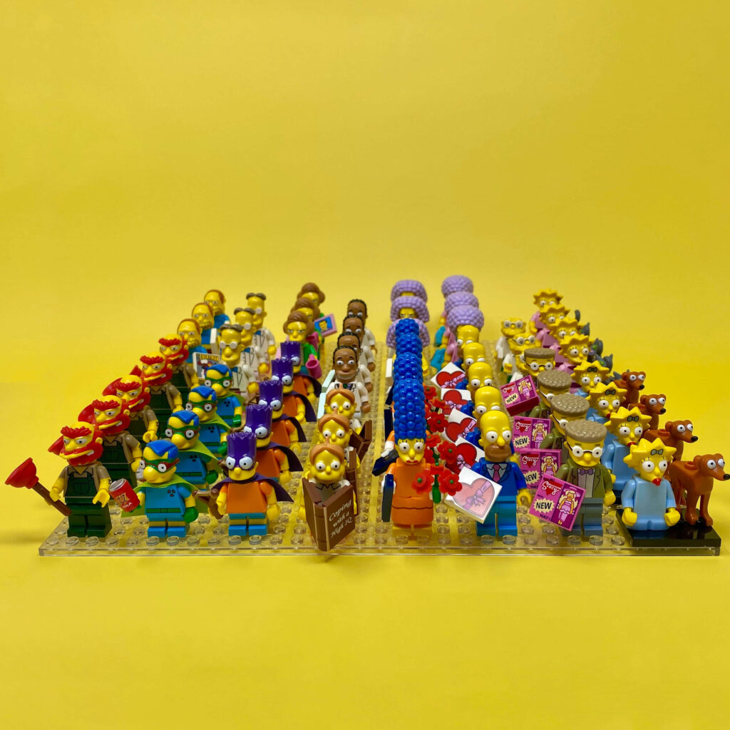 Colorful Lego Simpsons minifigures lineup with popular characters on bright yellow background Wallpaper