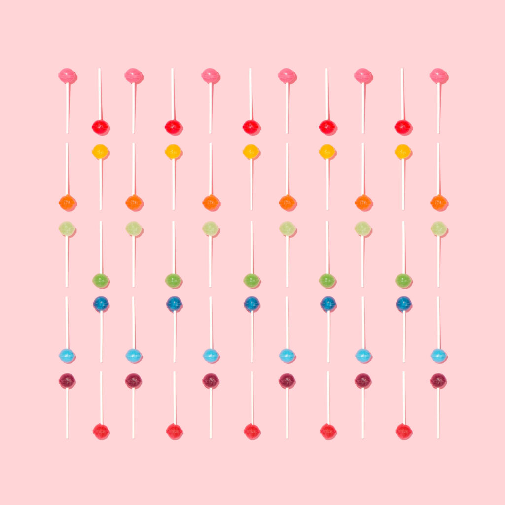Colorful lollipops pattern on soft pink background vibrant playful candy wallpaper design