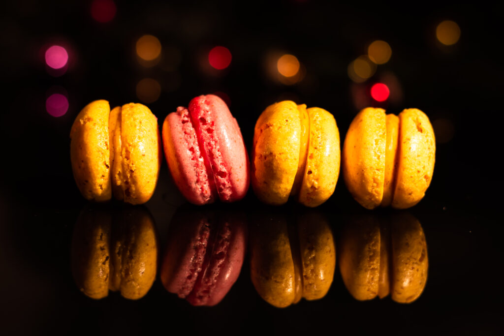 Colorful Yellow & Pink Macarons Wallpaper on Black Surface