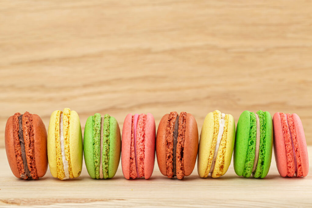 Colorful Macarons Wallpaper: Delightful Treats on Wood Background