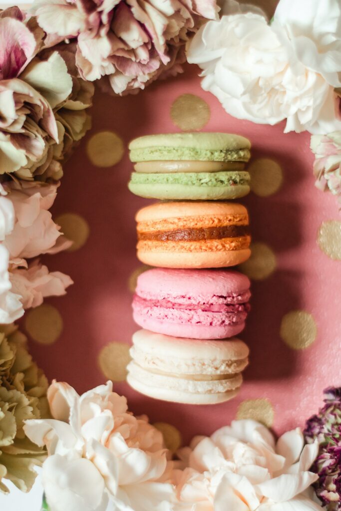 Charming Macaron Wallpaper: Colorful Treats on Pink Floral Background