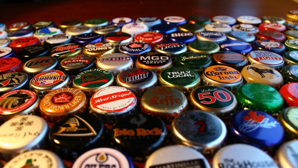 Colorful macro beer bottle caps including Labatt 50 Corona Light and Red Stripe textured wallpaper