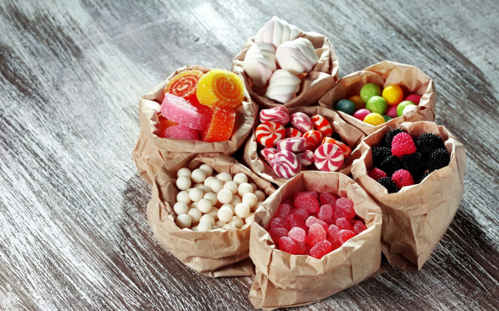 Rustic paper bags with colorful 3D marshmallows jelly sweets and peppermint candies on wood Wallpaper
