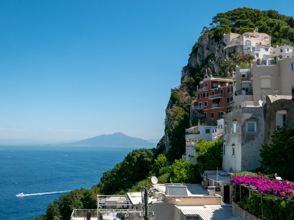Colorful Mediterranean houses on cliff by deep blue sea with lush greenery and mountain view Wallpaper