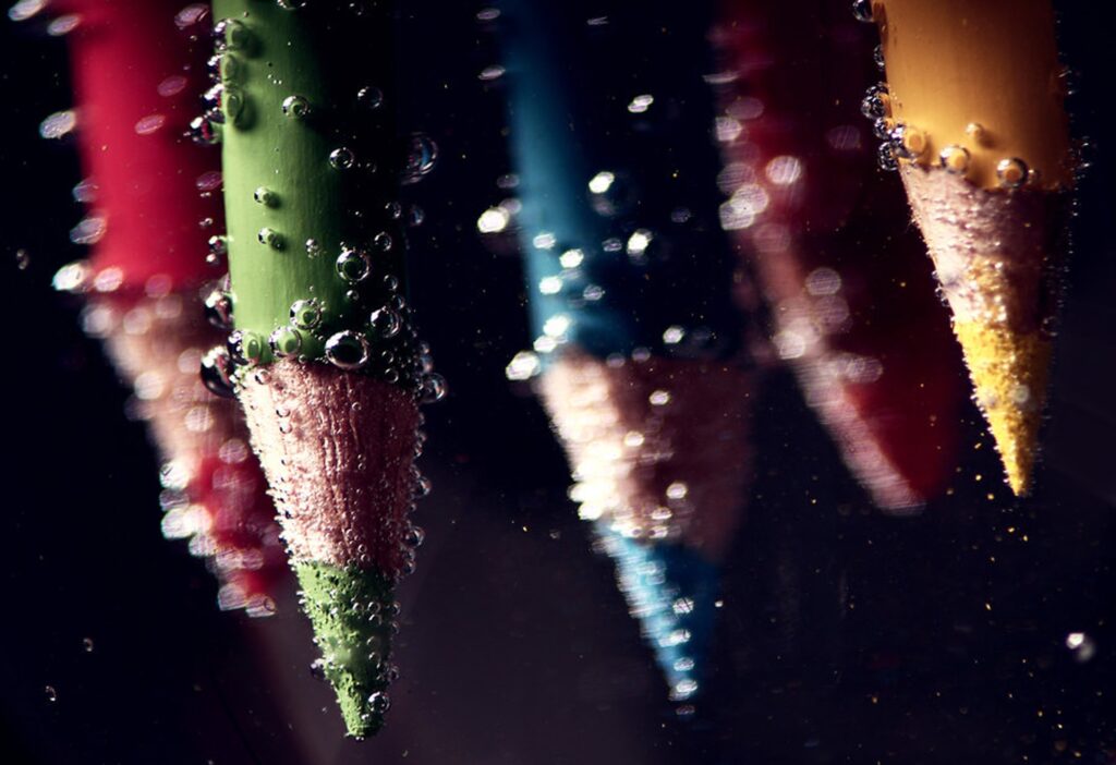 Vibrant Pencils in Water: Close-Up with Air Bubbles - Wallpaper Background