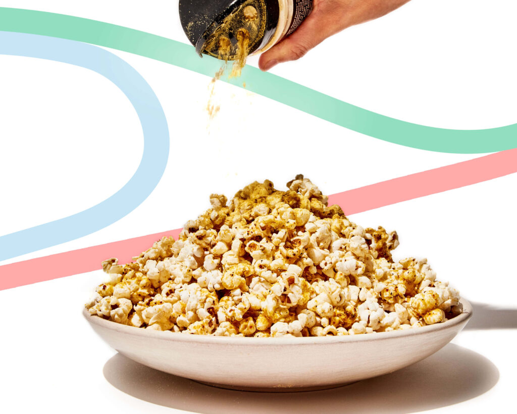 Dynamic Popcorn Seasoning Scene on a Clean White Background Wallpaper