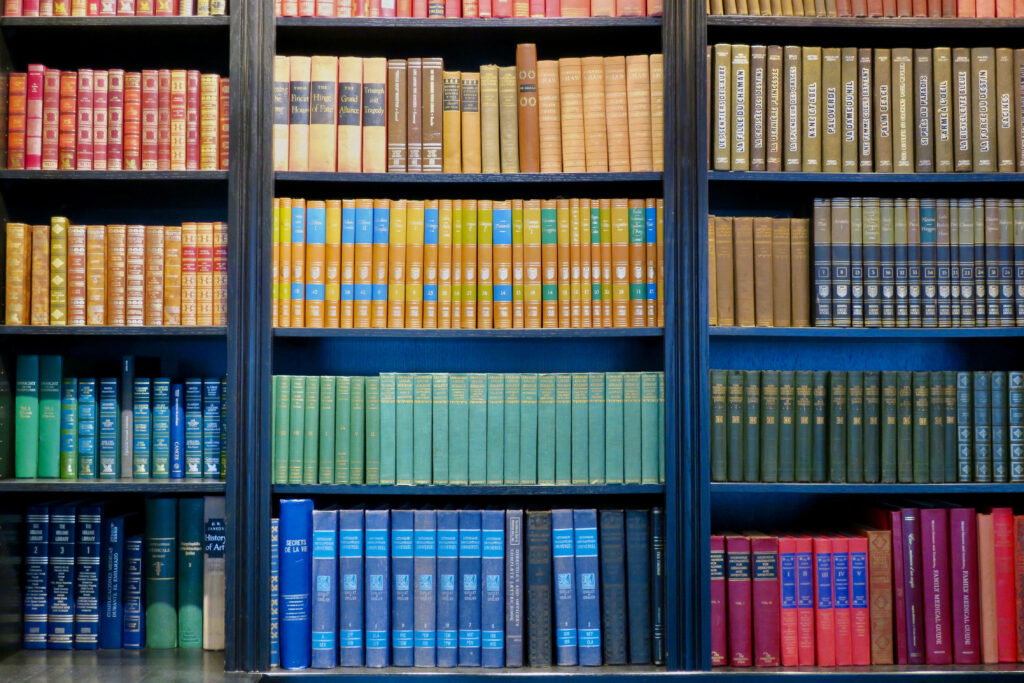Colorful library shelf with books arranged in a vibrant rainbow spectrum wallpaper background