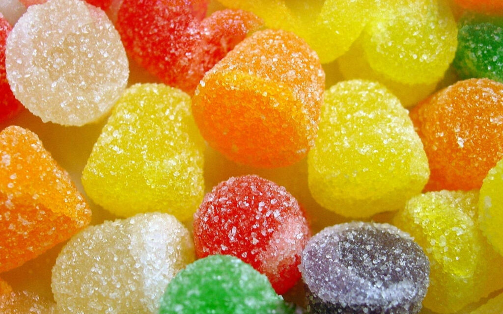 Colorful gumdrops coated with sparkling sugar crystals vibrant sweet candy wallpaper background