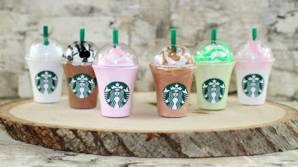Colorful Starbucks drinks with whipped cream and green straws on rustic wooden surface background Wallpaper
