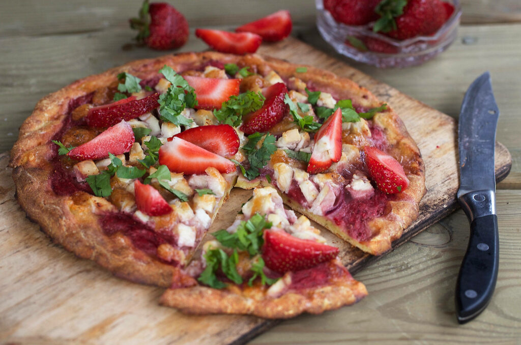 Colorful strawberry pizza with fresh slices cheese and herbs on rustic wooden board wallpaper